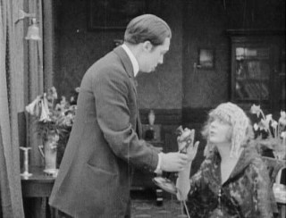 The friend arrives at the couple's home looking for his partner, but the phone rings . . .